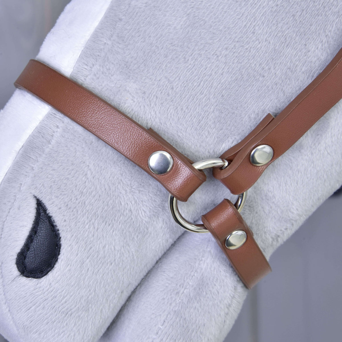 Close-up of a gray plush horse head wearing the Halter - brown leatherette by Hobby Horse LarDen, featuring silver rings and studs. A black embroidered eye is visible—a perfect accessory for any hobby horse collection.