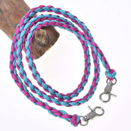 The Hobby Horse LarDen Reins Knitted Pinkie Blue, featuring blue and pink polypropylene rope with metal clasps at each end, are coiled on a white backdrop and draped over brown wood.