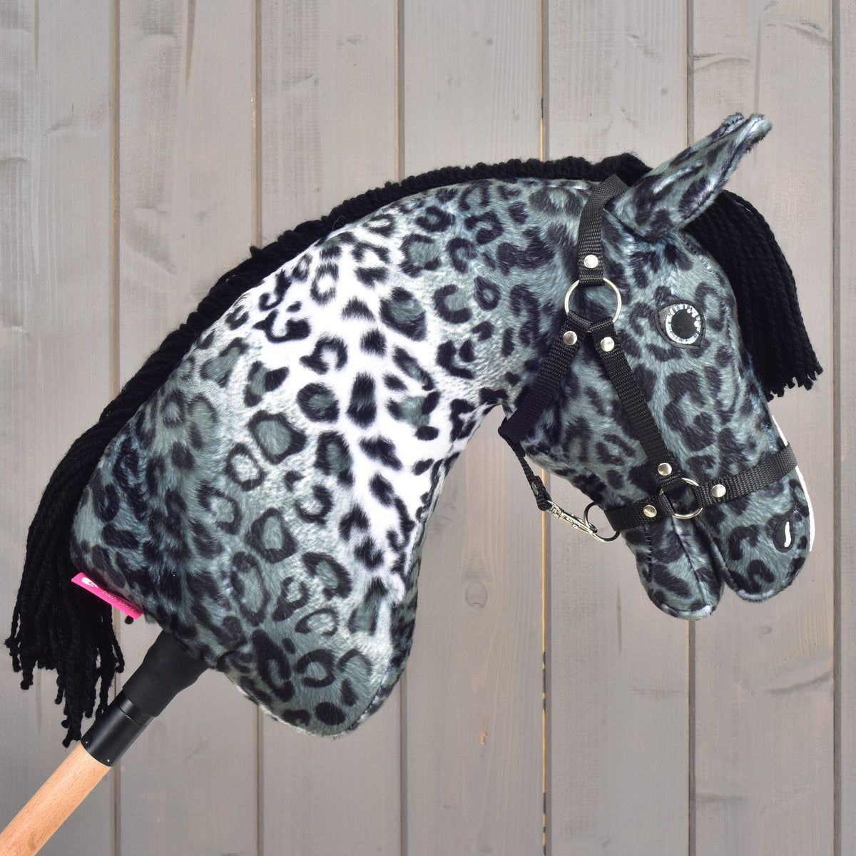 The Hobby Horse Picasso with Black Halter by Hobby Horse LarDen showcases a soft black and white leopard print pattern inspired by an Appaloosa’s spotted coat, complete with a black yarn mane and a black halter, displayed against a wooden background.