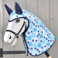 The Hobby Horse LarDen Raincoat Bubbles features a white face, black bridle, blue ears, and a light blue spotted blanket with all-weather accessories on a wooden stick, displayed before a wooden wall.