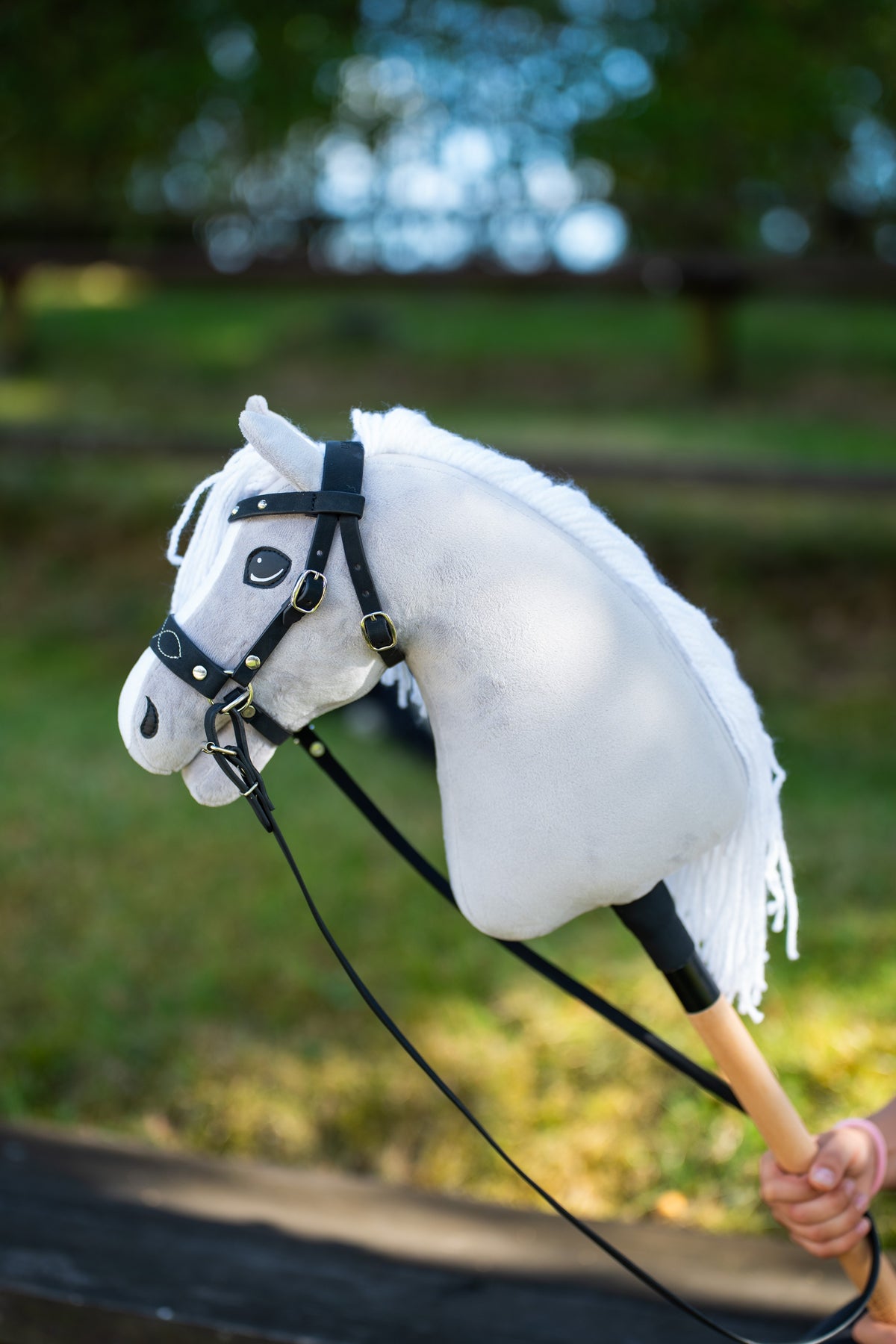 Hobby Horse Complete bitless bridle, decorated, on a light grey Hobby Horse outdoors with black reins