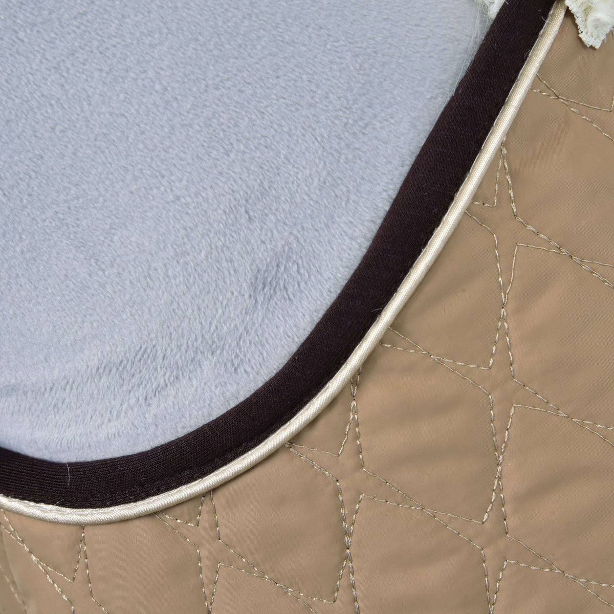 Detalje af stjerneformet quiltning på det beige stof med mørkebrun og cremefarvet kant mod gråt plys