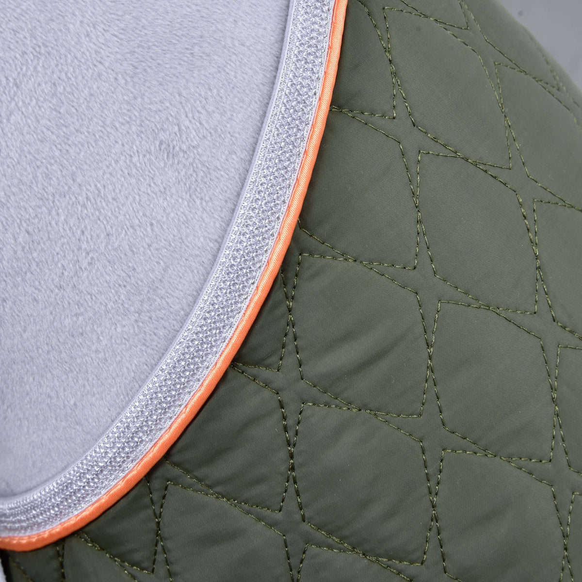 Close-up of Set Moos by Hobby Horse LarDen: quilted olive green fabric with diamond stitching, gray border, and silver trim with an orange edge—perfect as a stylish blanket or unique decor for your hobby horse.