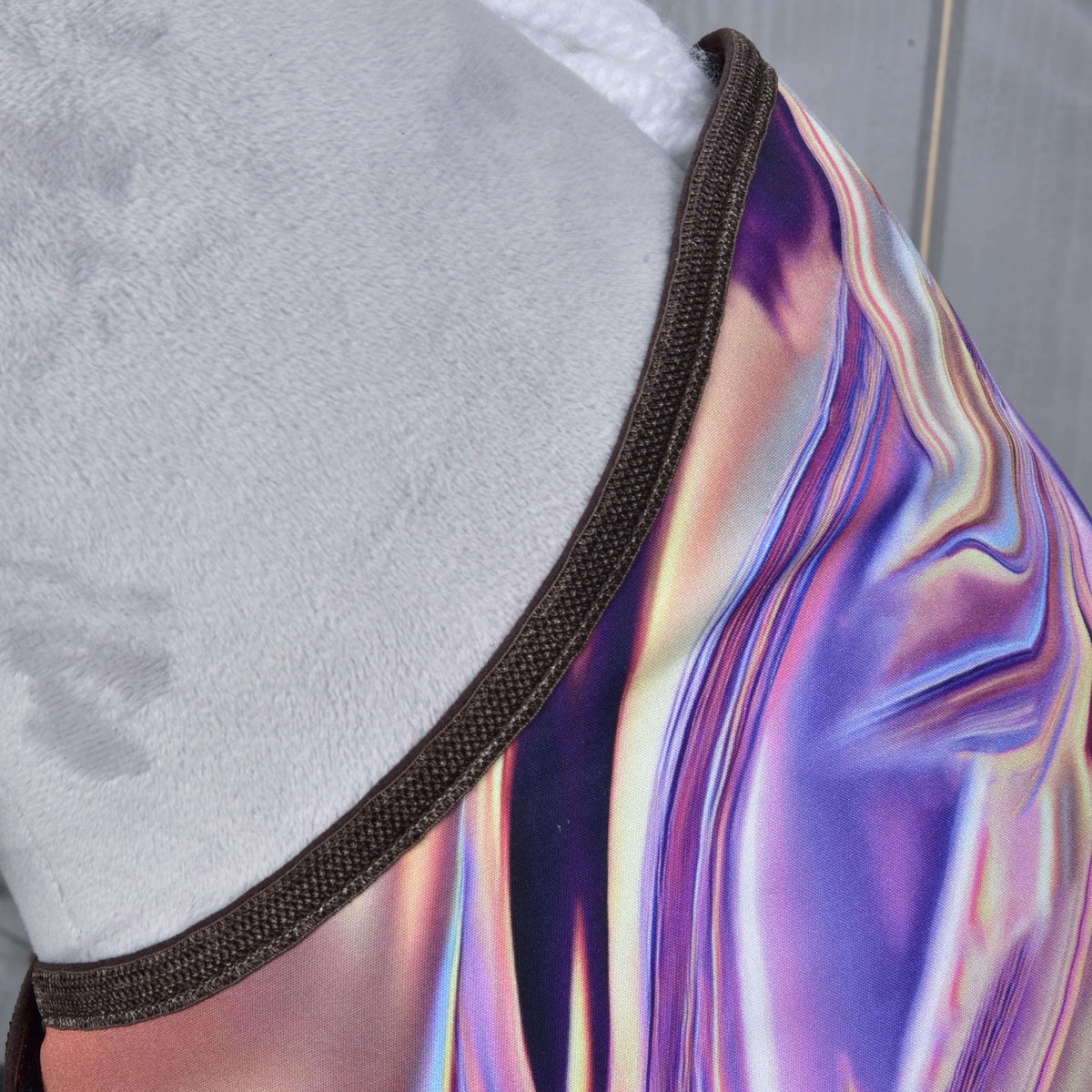 A close-up of Set Valery by Hobby Horse LarDen, featuring dark trim and iridescent, multicolored swirls of purple, pink, and gold fabric, draped over a soft light gray surface.