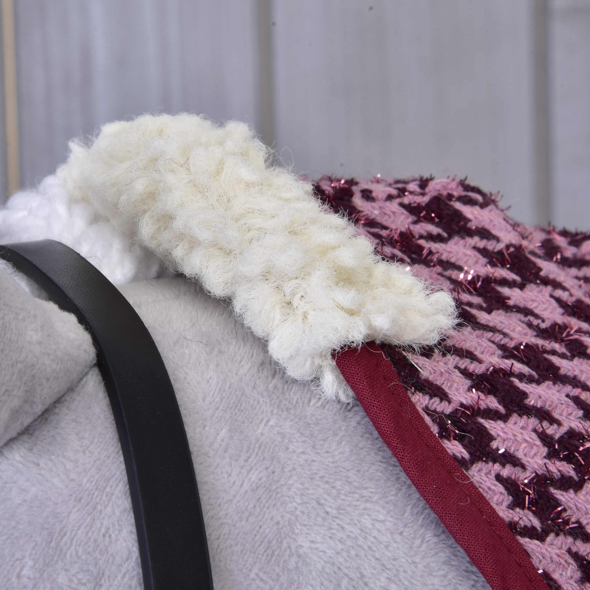 Close-up of the Set Harmony Elsa by Hobby Horse LarDen—a soft gray stable blanket with a black halter strap, topped with thick cream wool trim and pink-purple sparkly woven fabric. The warm, softly blurred background enhances its charm.