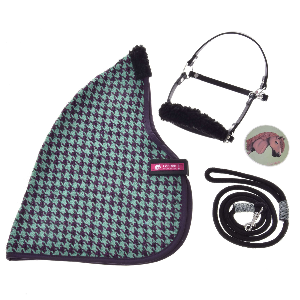 Flat lay of the Set Harmony Green by Hobby Horse LarDen: a green and black houndstooth-patterned stable blanket, black halter with fleece padding, black lead rope with silver clip, and a round horse-illustration pin.