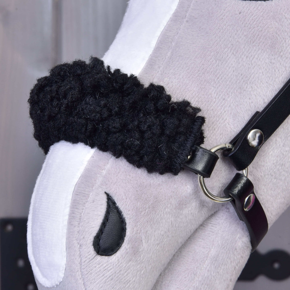 Close-up of the Hobby Horse LarDen Set Harmony Pink, showing its white and gray plush face, black halter and bridle with metal rings, plus an embroidered black teardrop-shaped eye.