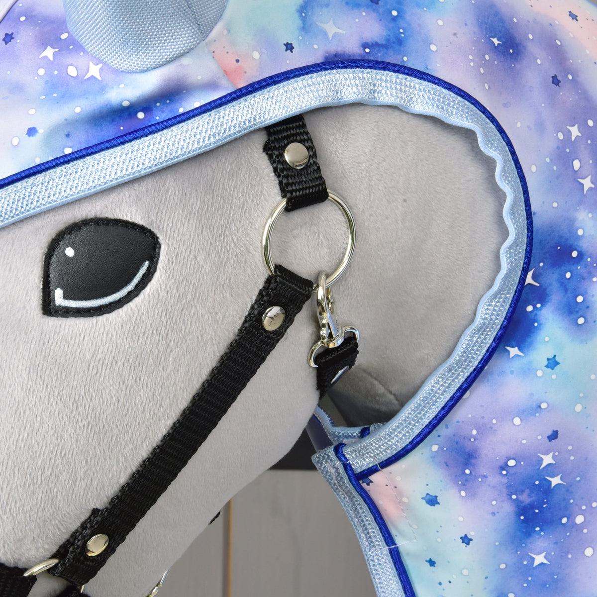 Close-up of a plush toy horse’s head in a black bridle and vibrant starry Space-patterned cover, paired with the Hobby Horse LarDen Raincoat Space—perfect for showcasing stylish hobby horse accessories in any weather.