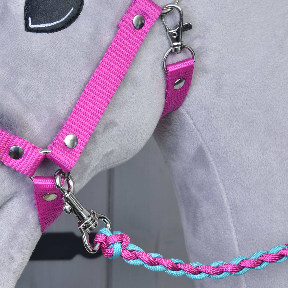 Close-up of a grey plush toy horse wearing the Set Perfect Combination Pink by Hobby Horse LarDen—a pink fur-padded halter with a braided blue and pink lead rope, attached with a silver clasp—ideal for hobby horse accessories fans.