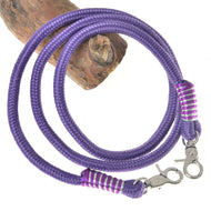 The Reins Viola by Hobby Horse LarDen features coiled purple polypropylene rope with swivel snap hooks and purple-white thread wrapping, making them ideal handmade reins for hobby horse fans—shown on a wooden log background.