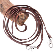 The Hobby Horse LarDen Split Western Reins Dark Brown, featuring a coiled design with metal clips at both ends, are displayed on wood against a white background.
