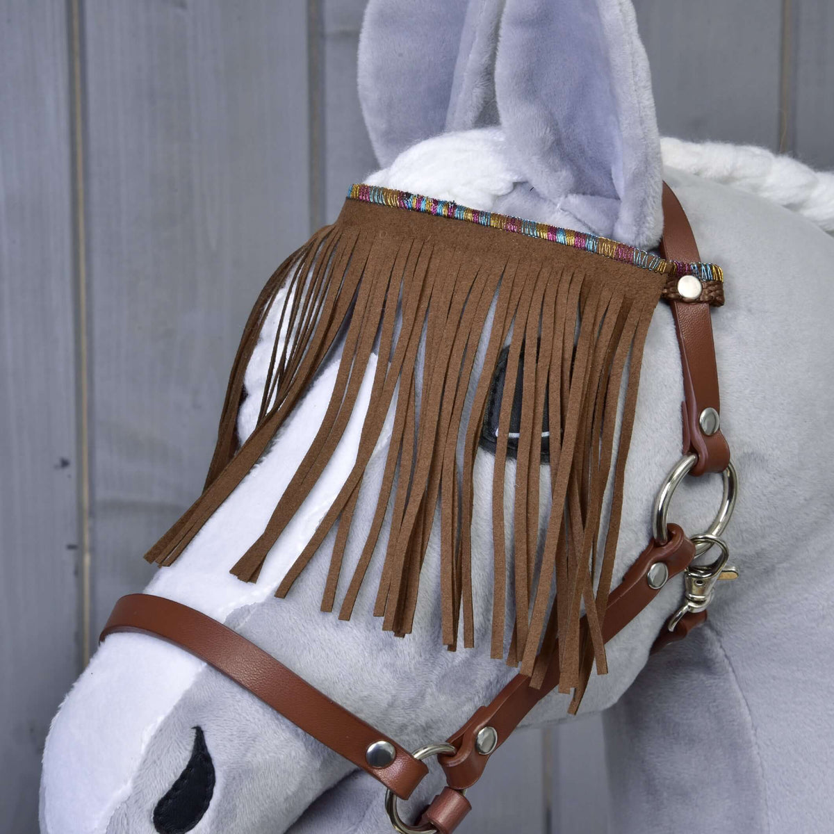 Nærbillede af det brune frynsede pandebånd med farverig vævet kant på den brune grime til Hobby Horse