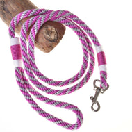 The Hobby Horse LarDen Lead rope stripe pink features pink, white, purple, and black braids with a metal clasp, coiled on wood against a white background.