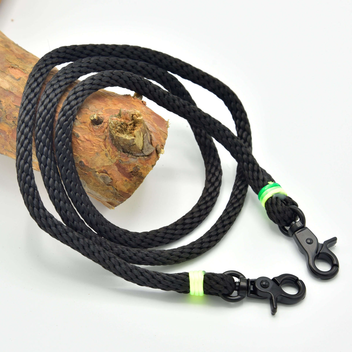 Reins Rainbow by Hobby Horse LarDen—a black braided rope leash with two metal clips and neon green bands, coiled on wood against a white background; ideal handmade reins for hobby horse enthusiasts.