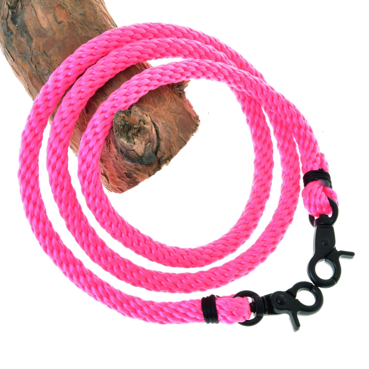 The Hobby Horse LarDen Reins Pink is a bright pink braided rope with black metal snap hooks on both ends, coiled on a tree branch—perfect for hobby horse reins.